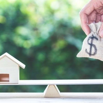 Picture of a house on one side and a bag of money on the other to achieve balance