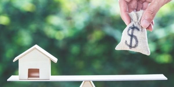 Picture of a house on one side and a bag of money on the other to achieve balance